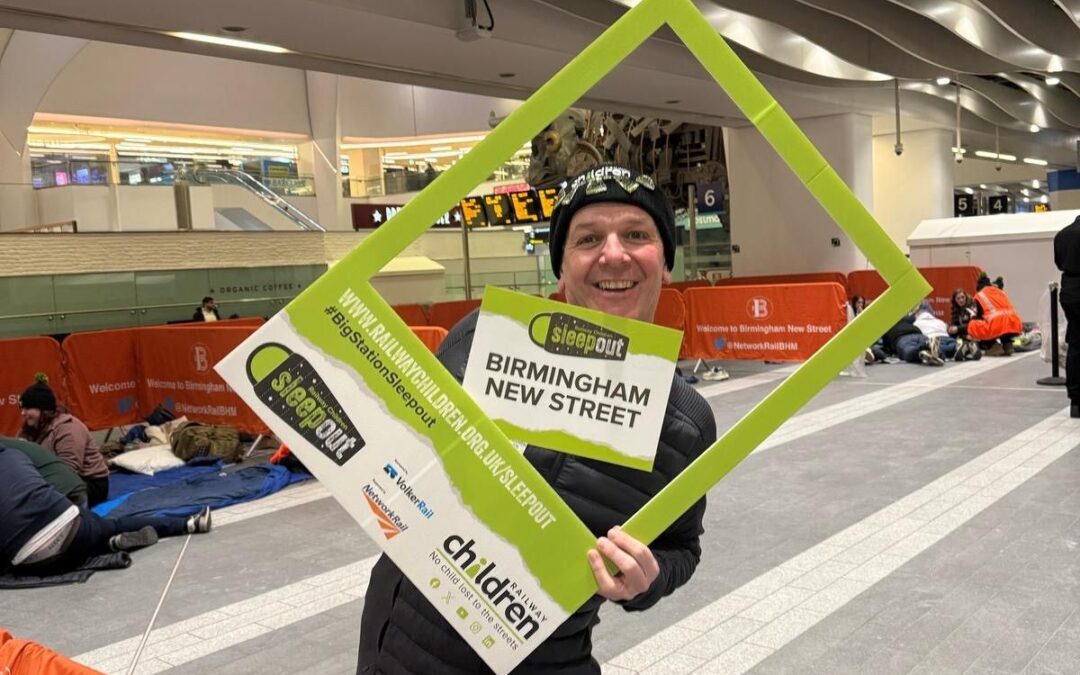 A man holding a green selfie frame and sign.