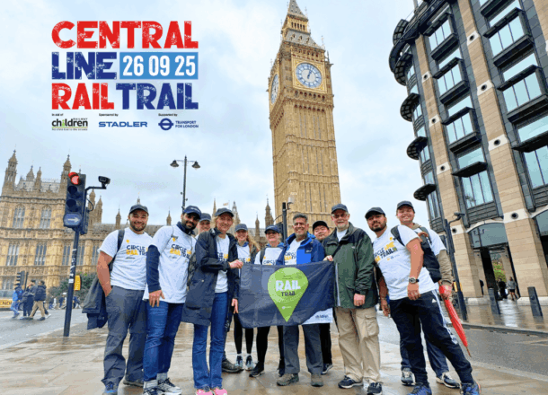 A group of people stood in front of Big Ben holding a Railway Children Rail Trail flag. Logo on image reads: Central line Rail Trail | Sponsored by Stadler | Supported by Transport for London.