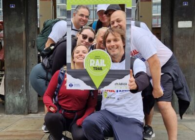 A group of Rail Trail participants huddled together to post behind a Rail Trail selfie frame.