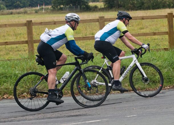 Two men cycling on a road as part of the Ride the Route challenge for Railway Children.
