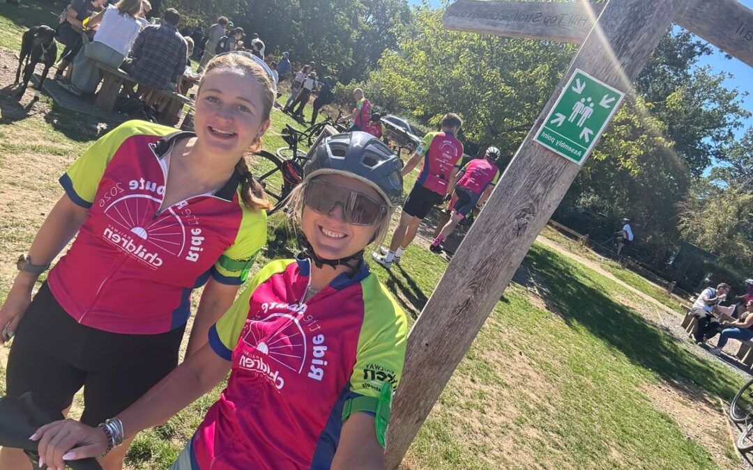 Two cyclists wearing pink and green jerseys taking a selfie.