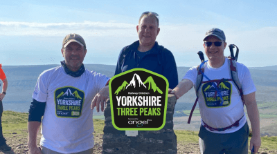 A group of people on the top of a mountain wearing Railway Children Yorkshire Three Peaks T-shirts.