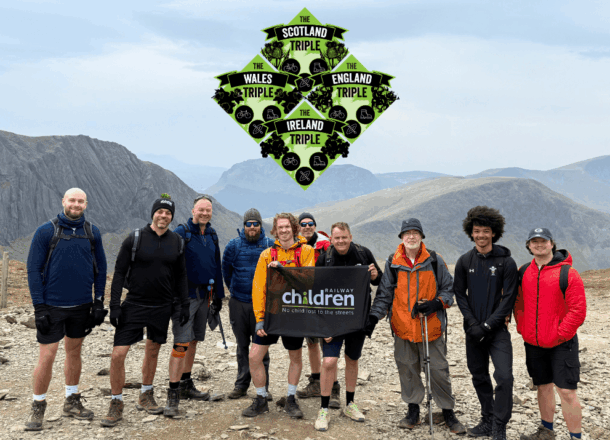 A group of people posing with a Railway Children flag in Snowdonia National Park. Above them is a logo showing The Triple Series: Scotland, Wales, England and Ireland.