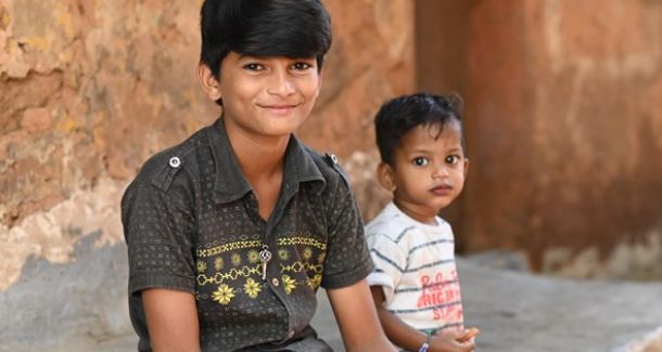Young boy sat on the floor with younger sibling.