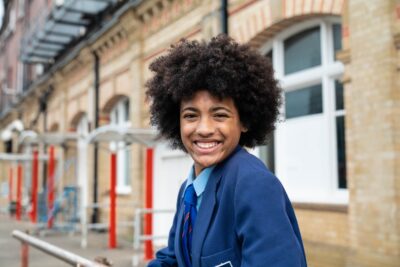 Teenage girl in a blue school uniform, smiling at the camera.
