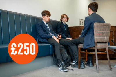 three teenage boys sat together in school uniform