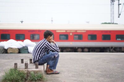 Indian boy sitting on train platform with head in hands