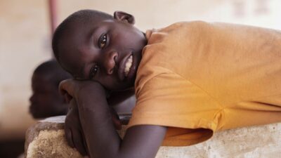 Young boy wearing an orange t-shirt lay on his side.