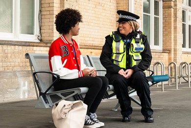 Teenage girl talking to BTP officer on a train station platform