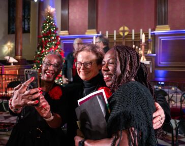 Three women taking a selfie in front of a christmas tree.