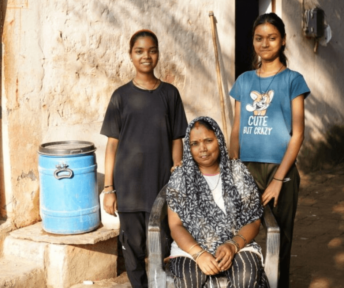 Indian family of three women smiling at camera outside home