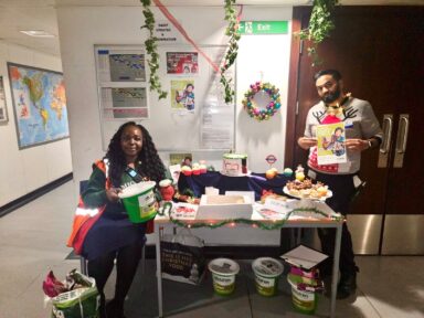 Man and woman stood at a fundraising table with baked goods/