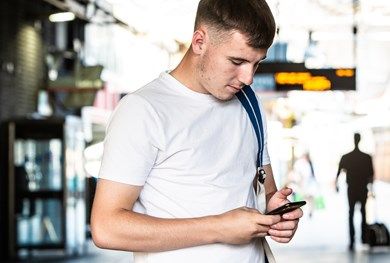 Teen boy on his phone in a train station.
