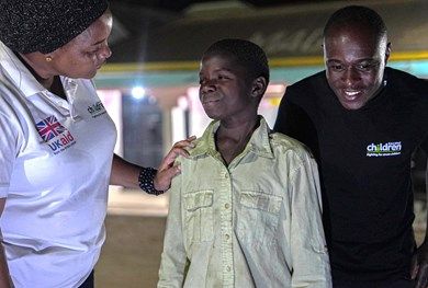 Young boy talking to two project workers at a station