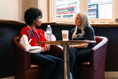Teen girl sat in a coffee shop with a female Railway Children worker.