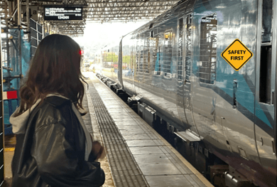 Dark haired girl at a platform looking at a train.