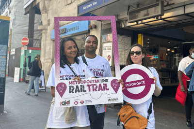 Three event participants holding Railway Children Metropolitan Line Rail Trail signage.