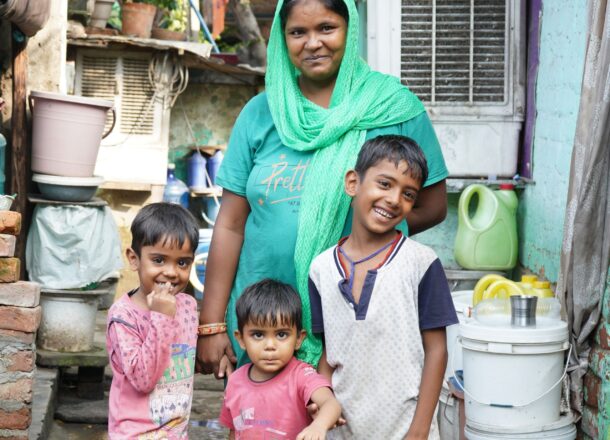 A woman stood with three young children, standing outside.