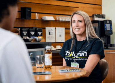 Railway children worker smiling in coffee shop speaking to child.