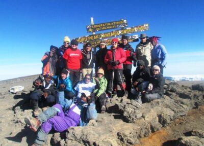 Trekkers on top of Mount Kilimanjaro next to the famous sign.