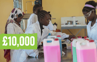 A group of young women in a lab wearing safety goggles and white jackets and surrounded by different coloured bottles. Text on image reads: £10,000.
