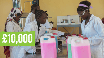 A group of young women in a lab wearing safety goggles and white jackets and surrounded by different coloured bottles. Text on image reads: £10,000.