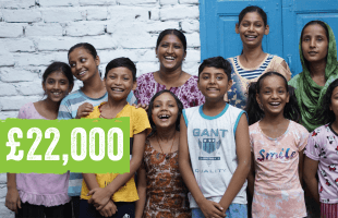 A group of children with Railway Children project workers at a project in India looking happy. Text on image reads: £22,000.