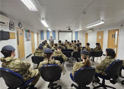 Group of young people wearing army uniform sat listening to a talk.