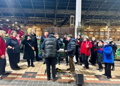 A group of people singing in a train station.