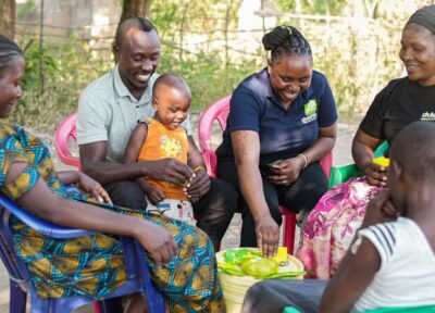 Youth practitioners in Tanzania sat with a family.