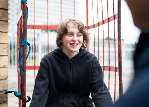 Young teenage boy black hoodie smiling near train station
