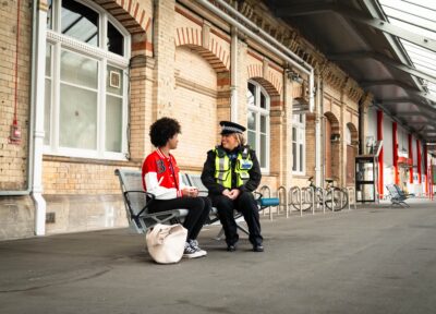 Police officer speaking to teenage girl at train station