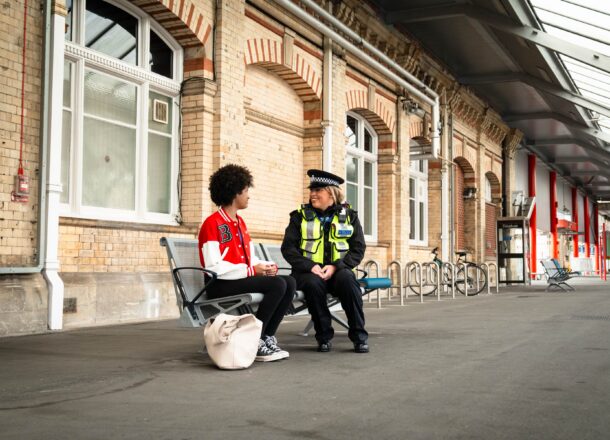 Police officer speaking to teenage girl at train station
