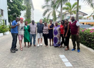 Group of people smiling at camera with palm trees behind