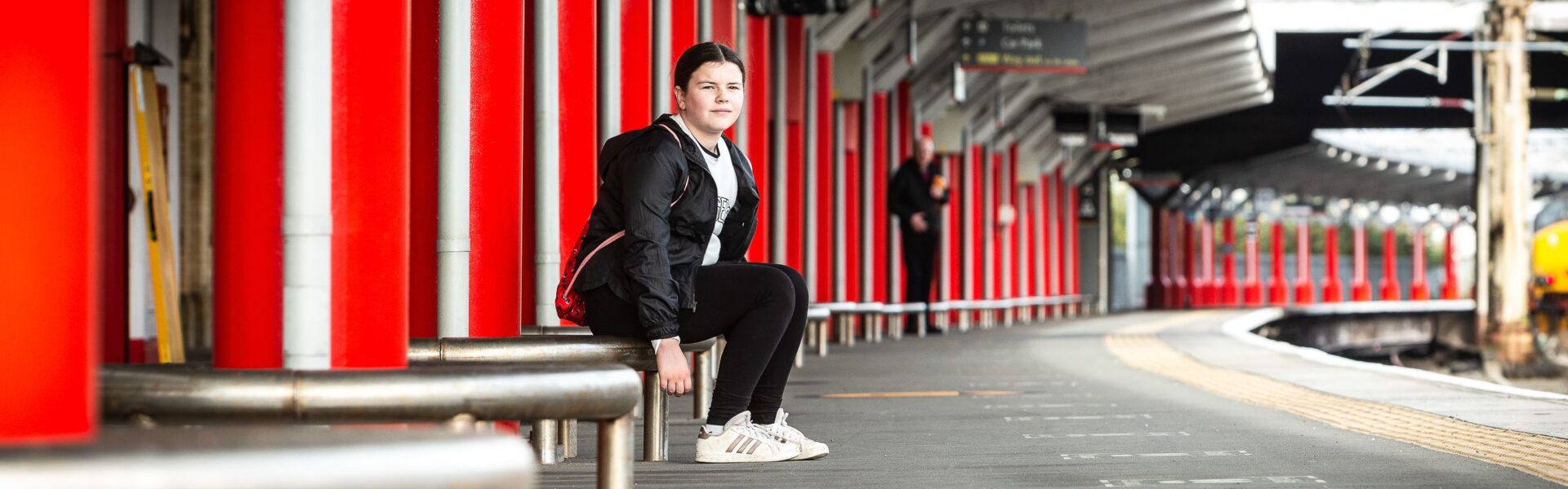 Young teenage girl sitting on train station platform