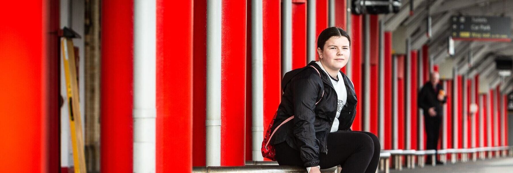 Young teenage girl sitting on train station platform.