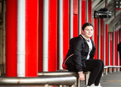 Young teenage girl sitting on train station platform.