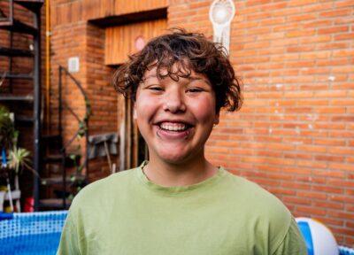 Young LGBTQ+ person with green t-shirt smiling