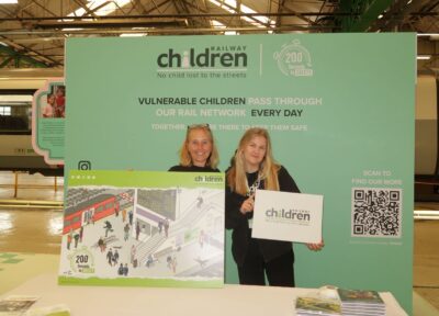 Railway Children backdrop with two women holding boards.