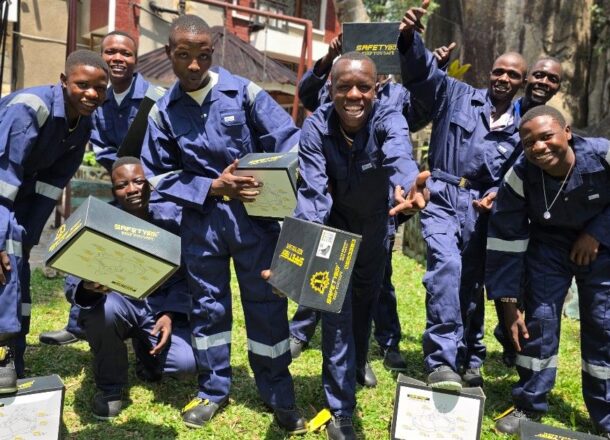 A group of young adults at a Youth Association graduation ceremony showing the safety gear they have received and celebrating officially joining technical colleges and apprenticeships.