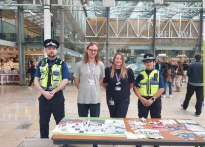 A group of people stood behind a desk at a railway station with two British Transport Police officers.