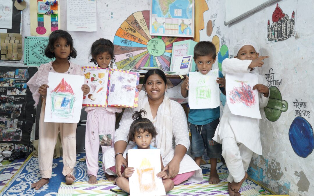 A group of children at a Child Activity Centre stood showing the drawings they have done with a Railway Children India project worker.