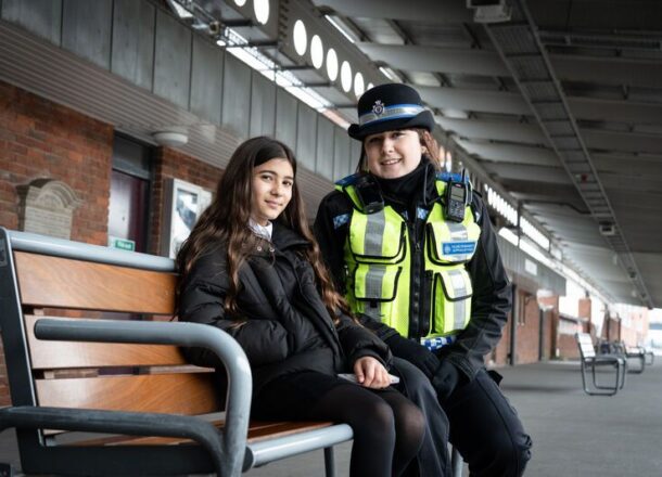 British Transport Police female officer sat with young teenager girl at a train station.