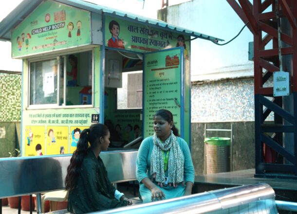 A teenage girl sat with a Railway Children India project worker at a Railway Station.
