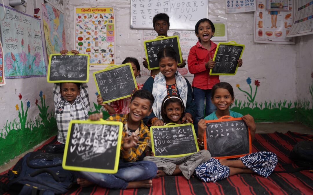A group of children showing chalkboards with numbers and figures on at a Child Activity Centre in India.