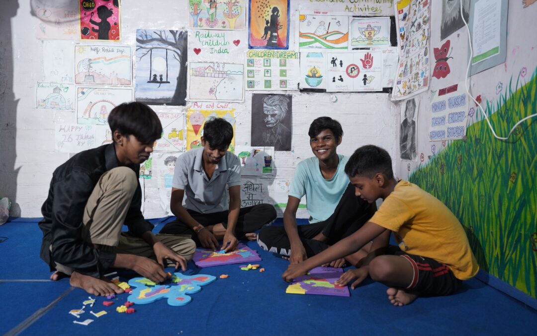 A group of boys sat on the floor looking at some work at a Child Activity Centre in India.
