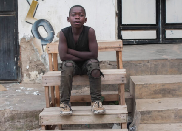 A boy sat on some steps on the streets of Tanzania.