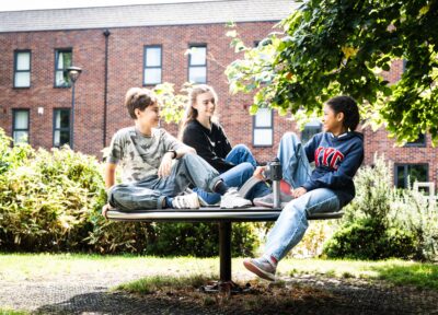 A group of three younger children sat on a merry-go-round at a park in the UK.
