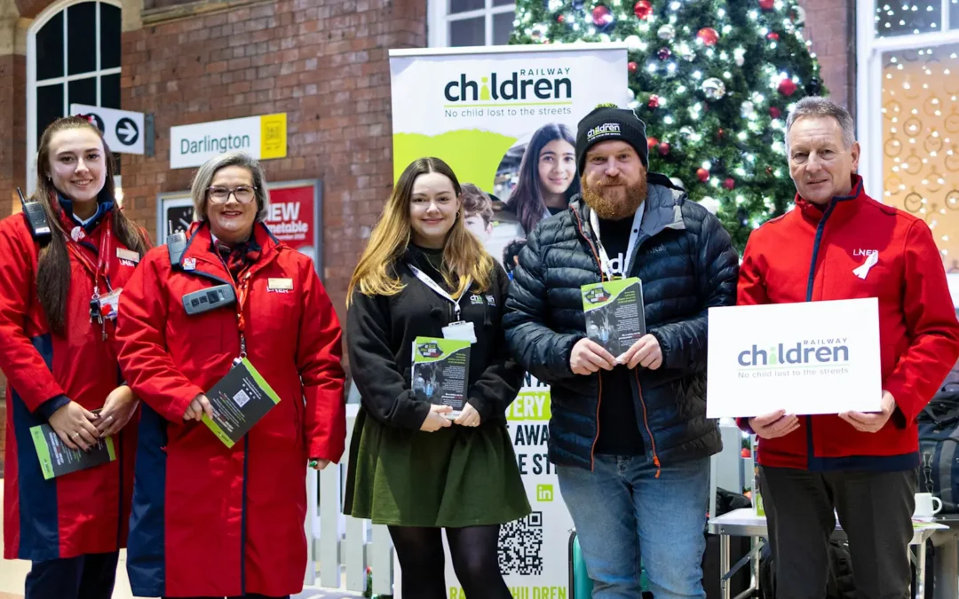 Railway Children and LNER staff stood posing at a station in the UK.