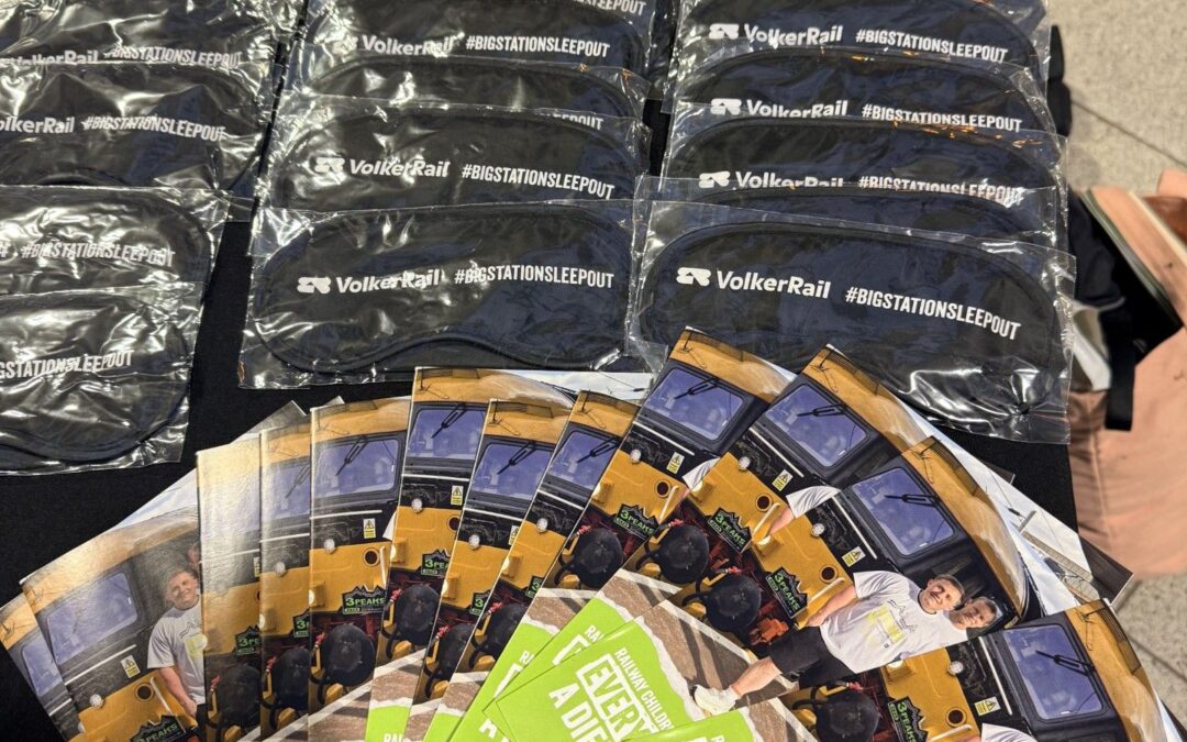 Table display featuring branded sleepout merchandise including beanie hats. VolkerRail branded sleep eye masks and promotional leaflets for Railway Children charity.